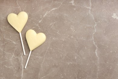 Chocolate heart shaped lollipops on light grey marble table, flat lay. Space for text