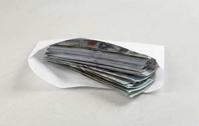 Photo of Envelope with dollar bills on light grey stone table. Bribe concept