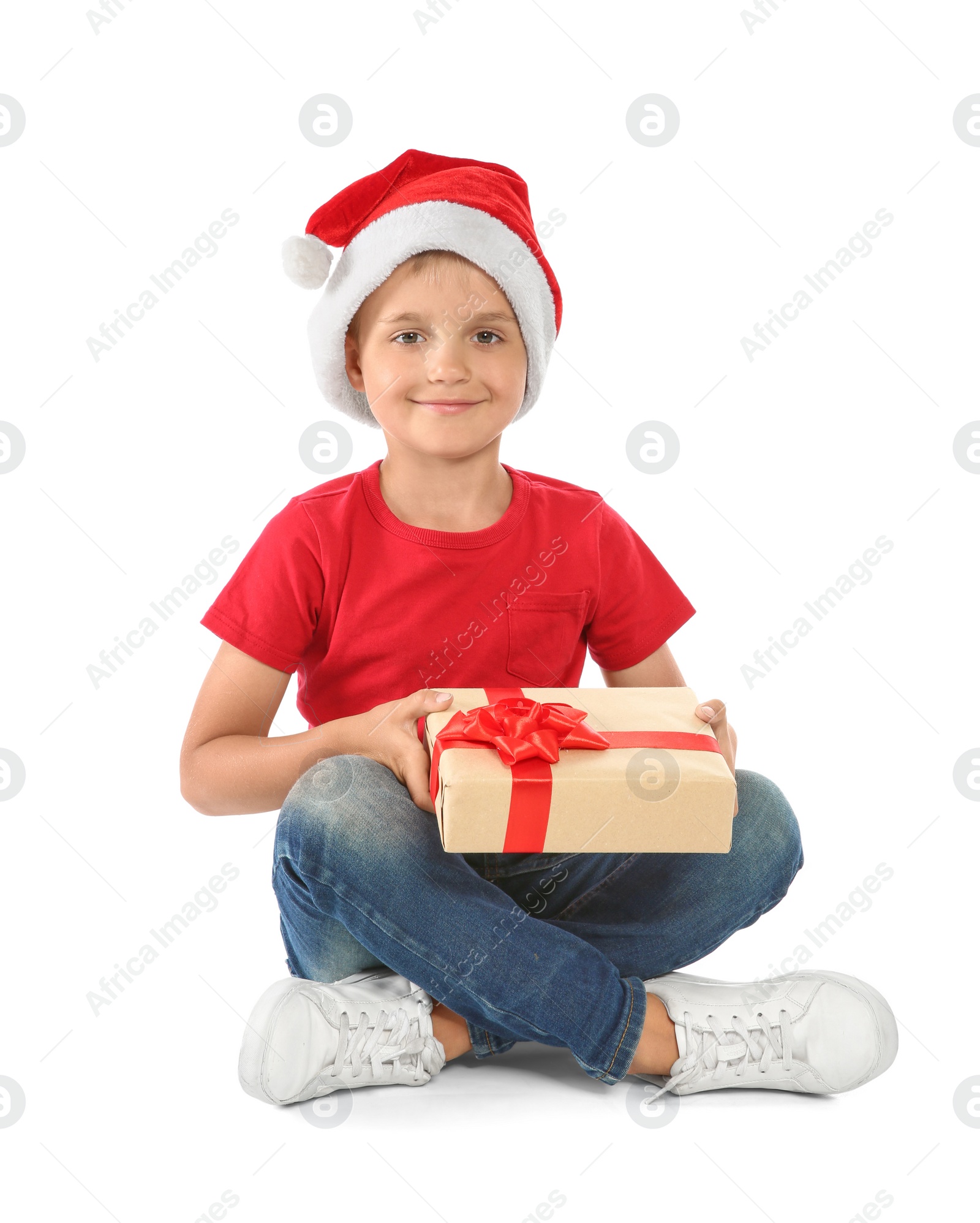 Photo of Cute little child in Santa hat with Christmas gift on white background