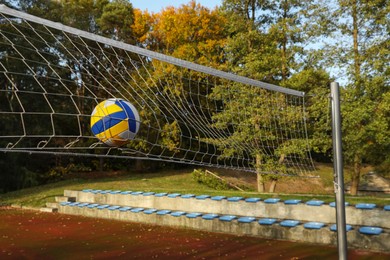 Photo of Ball hitting into volleyball net on court outdoors