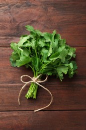 Photo of Bunch of fresh coriander on wooden table, top view