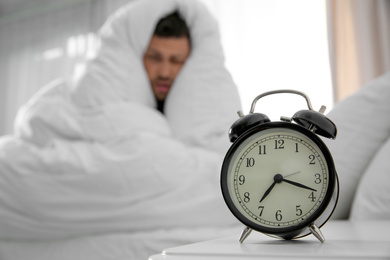 Photo of Alarm clock and man at home in morning. Space for text