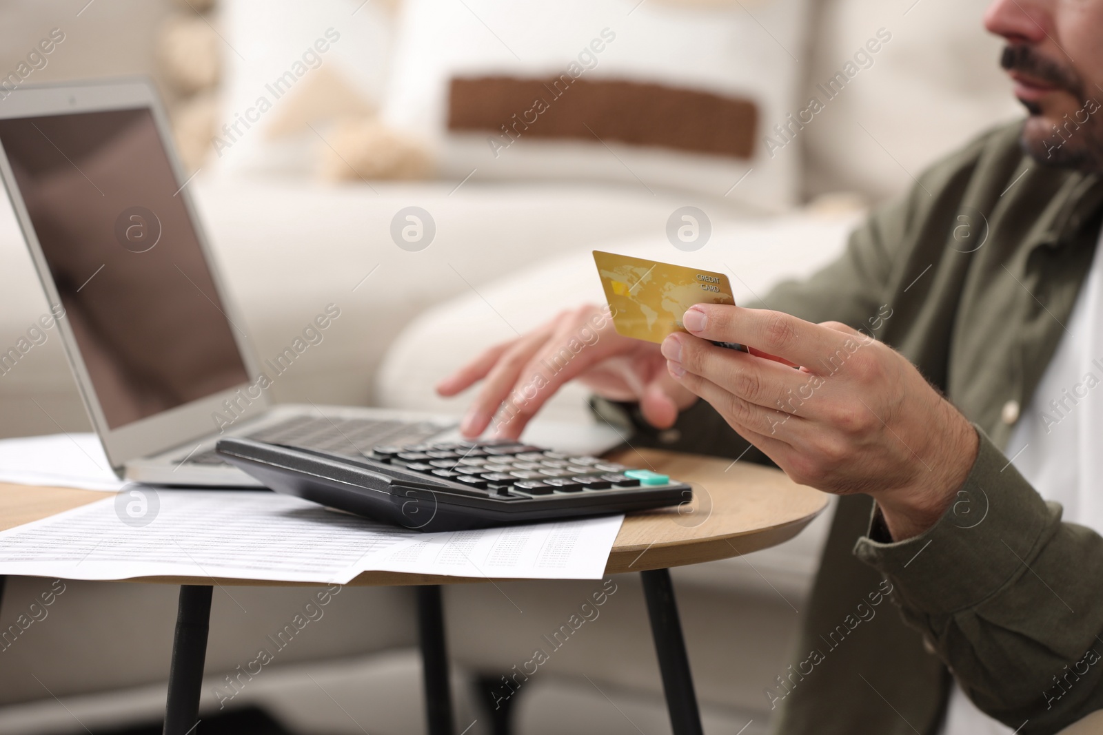 Photo of Man with laptop, calculator and credit card planning budget at table indoors, closeup. Debt problem
