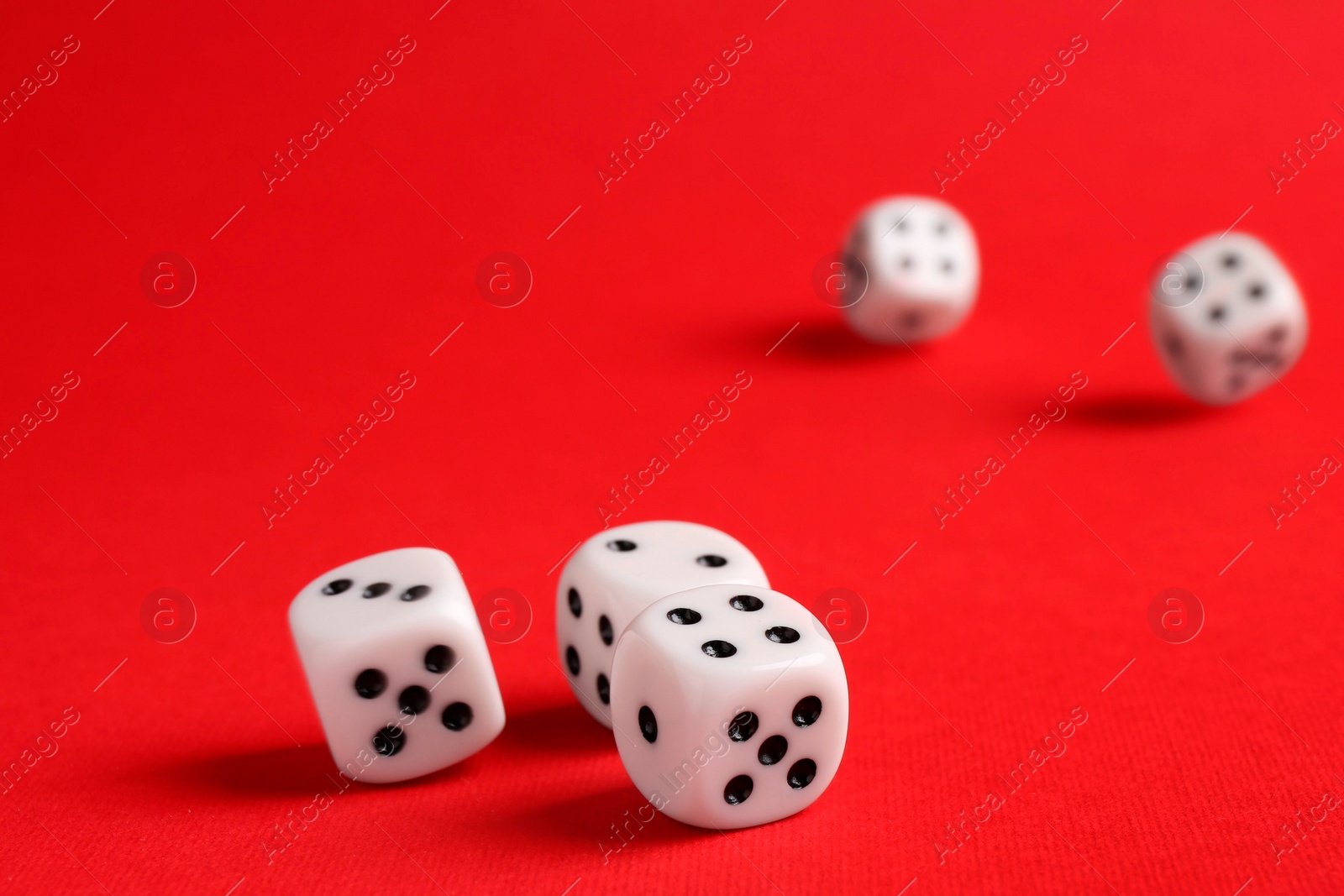 Photo of Many white game dices falling on red background. Space for text