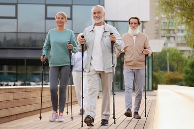 Group of senior people performing Nordic walking outdoors. Low angle view