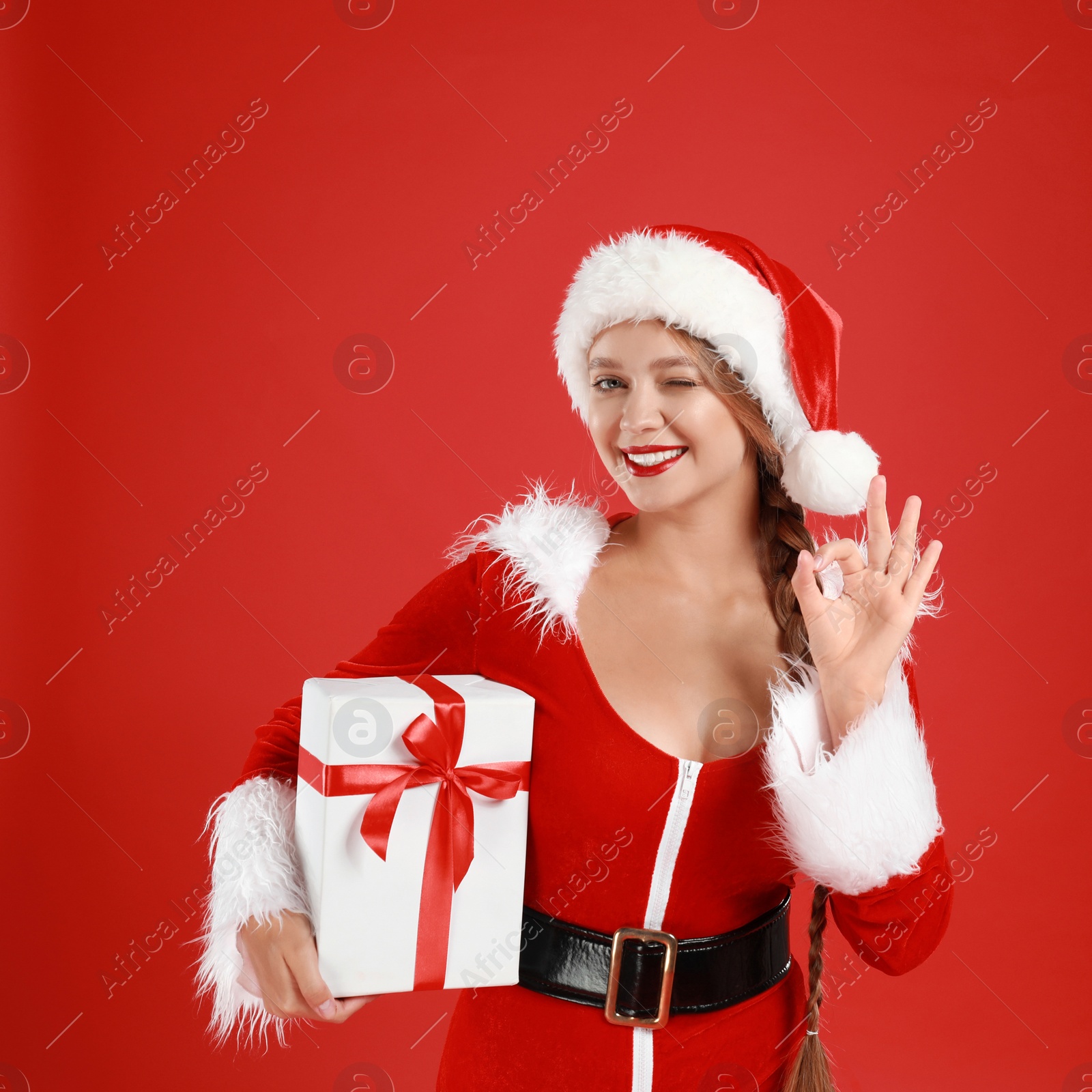 Photo of Beautiful Santa girl with Christmas gift on red background