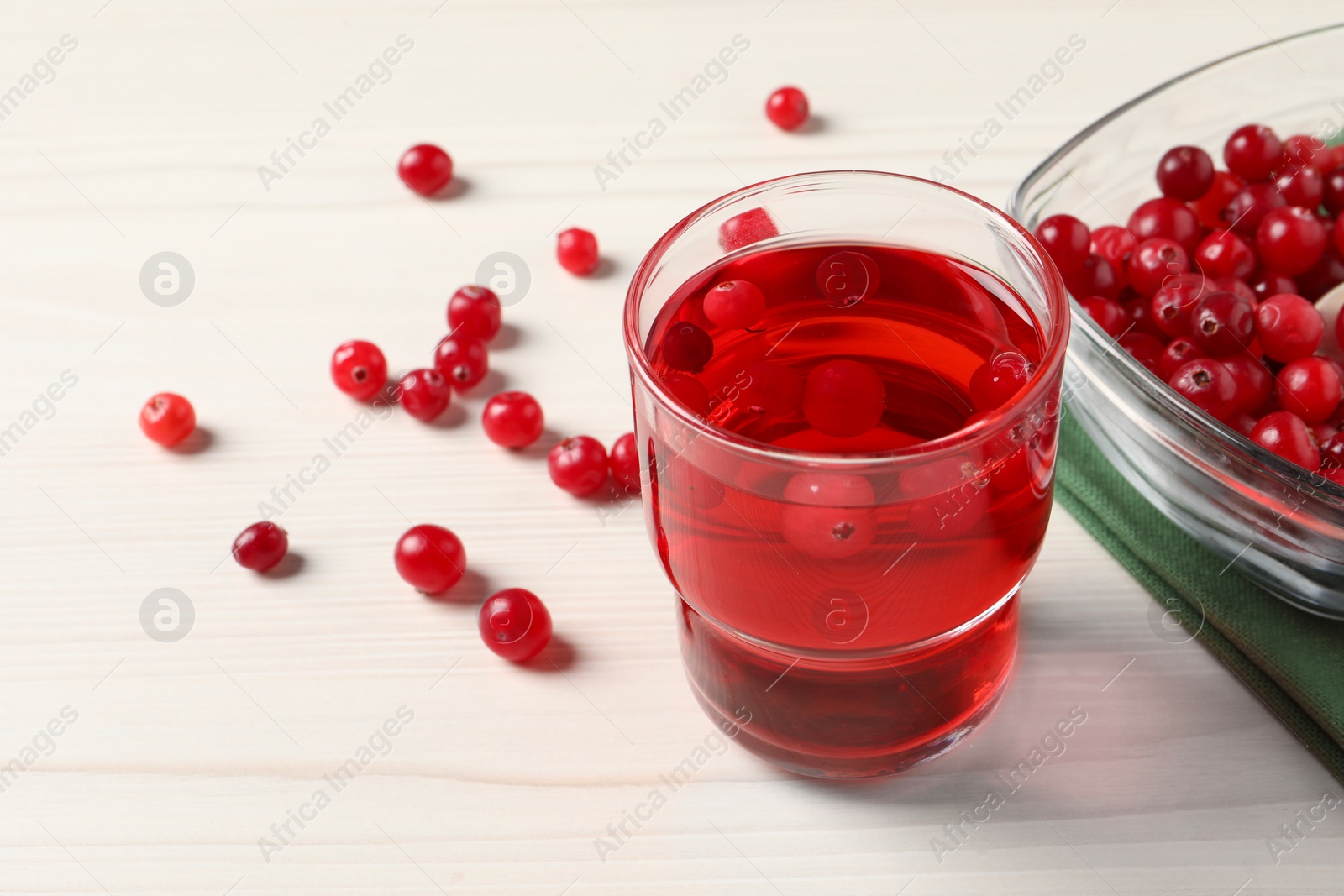 Photo of Tasty cranberry juice in glass and fresh berries on white wooden table, closeup. Space for text