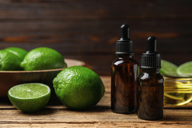 Photo of Lime essential oil and cut citrus fruits on wooden table