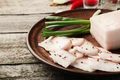 Photo of Tasty salt pork with green onion served on wooden table