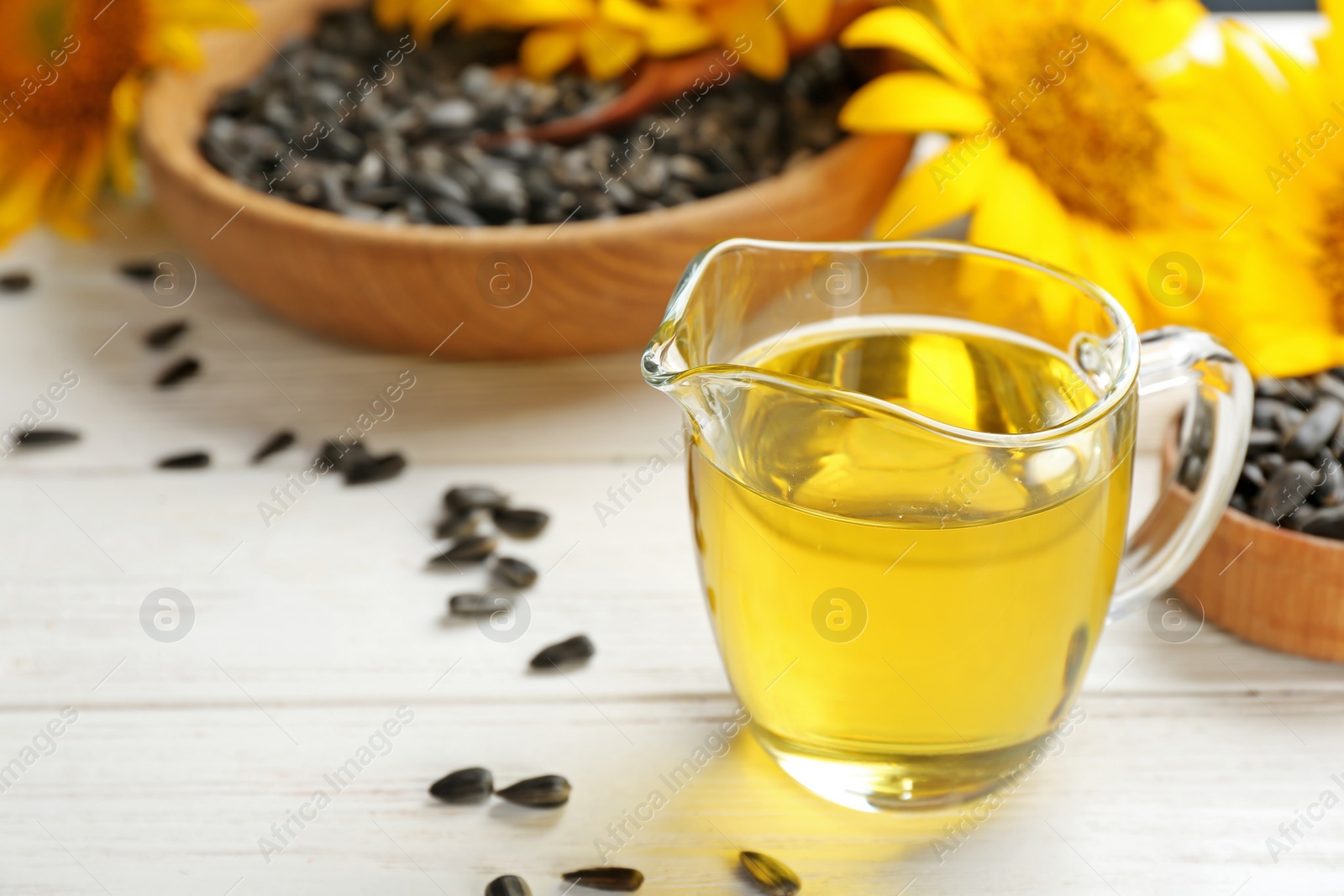 Photo of Jug of sunflower oil and seeds on table