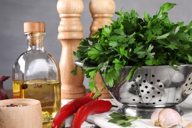Photo of Colander with fresh parsley, spices and other products on table, closeup