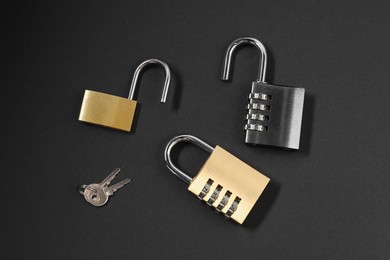 Photo of Different padlocks on black background, flat lay