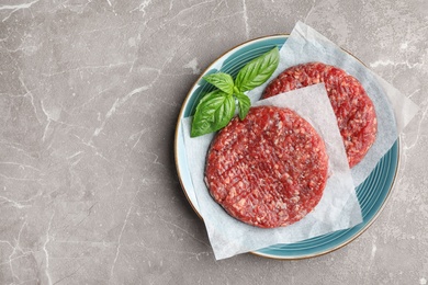 Photo of Raw meat cutlets for burger on marble table, top view. Space for text