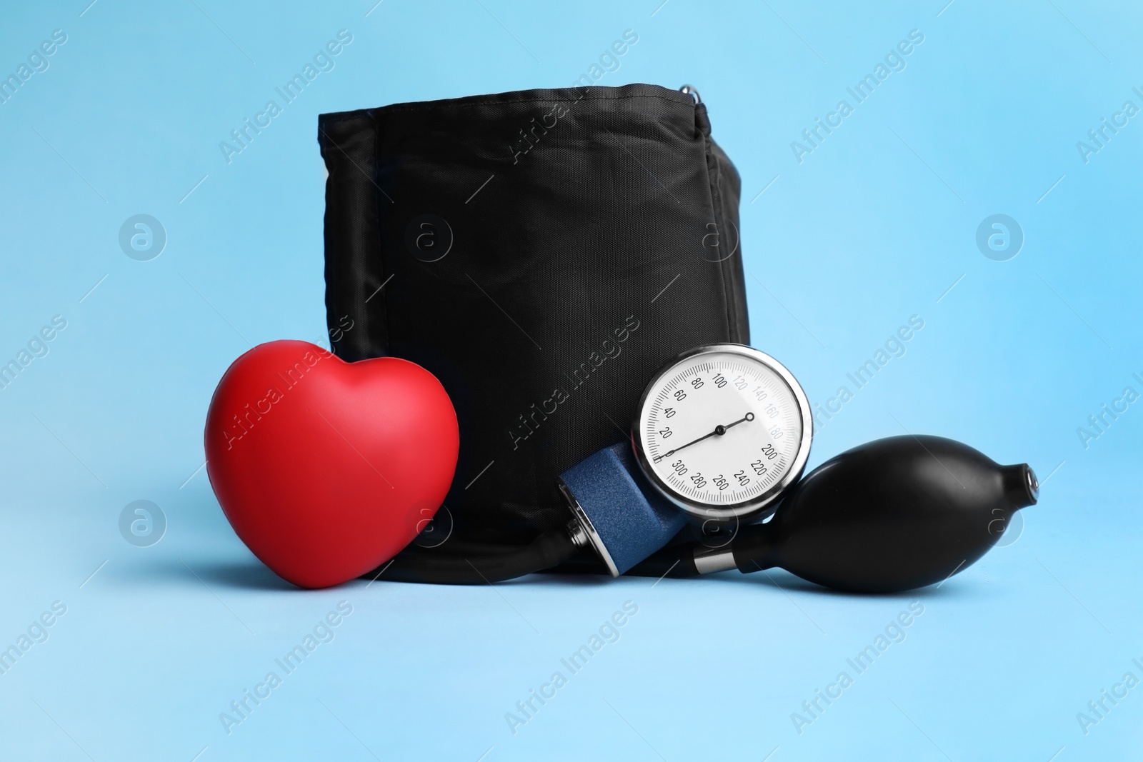 Photo of Blood pressure meter and toy heart on light blue background