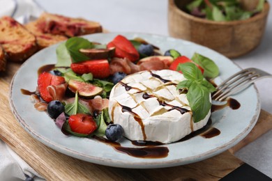Delicious salad with brie cheese, berries and balsamic vinegar on board, closeup