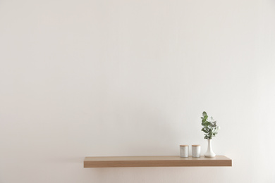 Wooden shelf with decorative elements on light wall