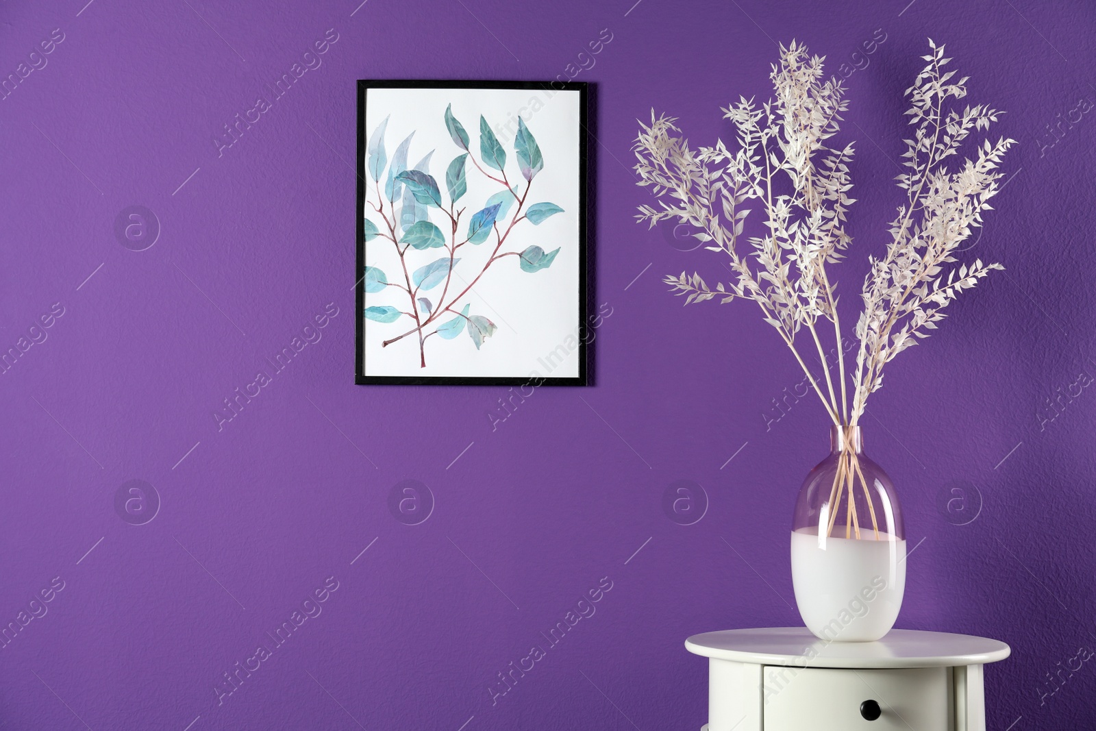 Photo of Elegant vase with beautiful branches on table near purple wall