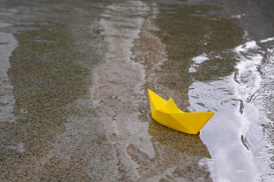 Photo of Beautiful yellow paper boat on water outdoors, space for text