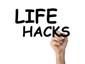 Man writing words Life Hacks with marker on glass board against white background, closeup