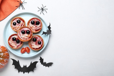 Photo of Cute monster tartlets served on white table, flat lay with space for text. Halloween party food