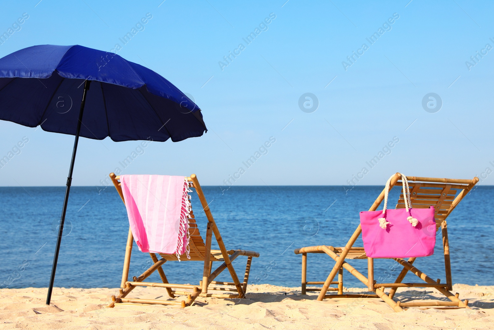 Photo of Empty wooden sunbeds and beach accessories on sandy shore