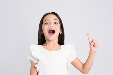 Portrait of cute little girl on light grey background