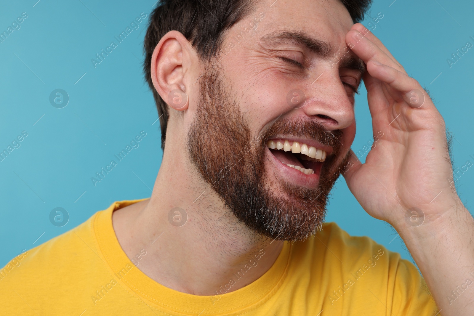 Photo of Handsome man laughing on light blue background, closeup