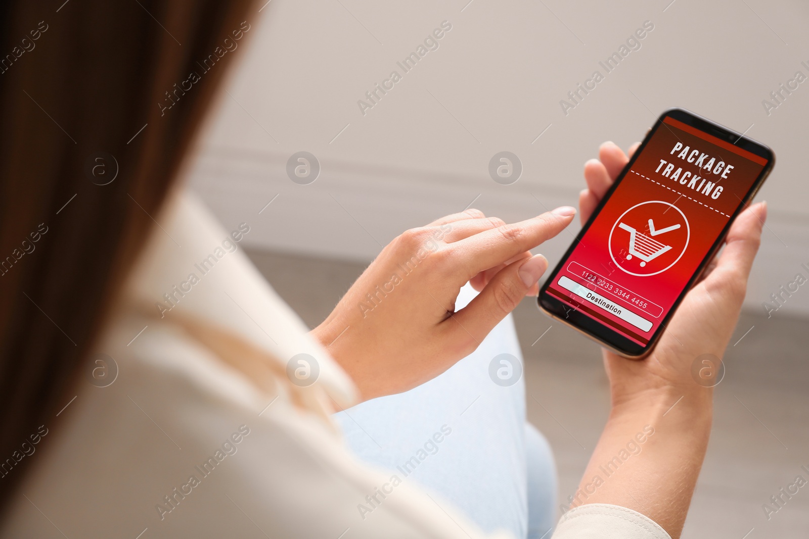 Image of Woman tracking parcel via smartphone indoors, closeup