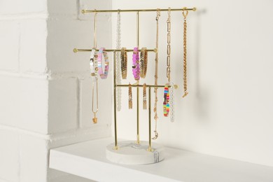 Photo of Holder with set of luxurious jewelry on white shelf