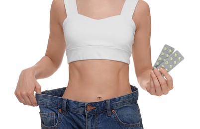 Photo of Slim woman in big jeans with pills on white background, closeup. Weight loss