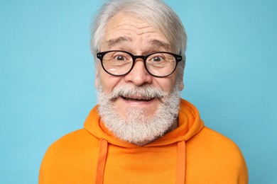 Senior man with mustache on light blue background