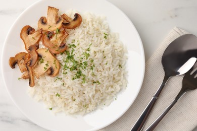 Photo of Delicious rice with parsley and mushrooms served on white marble table, flat lay