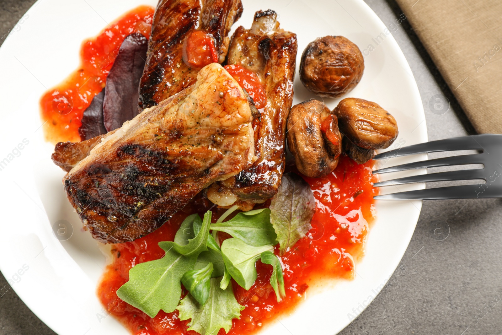 Photo of Delicious grilled ribs served on grey table, top view