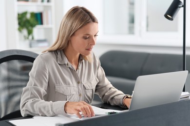 Photo of Businesswoman working with documents at grey table in modern office