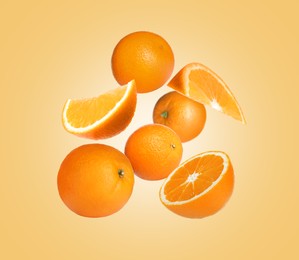 Image of Cut and whole oranges flying on pale orange background