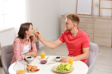 Photo of Happy young couple having breakfast at table in room