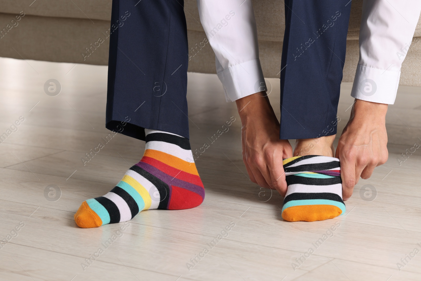 Photo of Man putting on colorful socks indoors, closeup