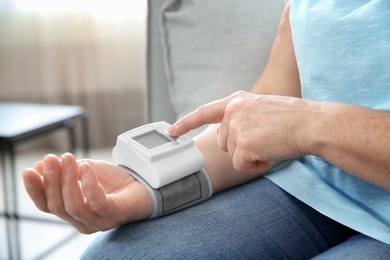 Photo of Mature woman checking pulse with medical device at home, closeup