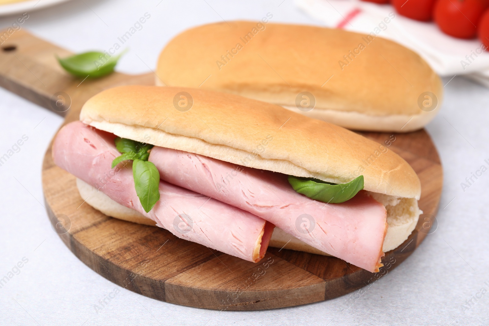 Photo of Delicious sandwich with ham and basil on white table, closeup