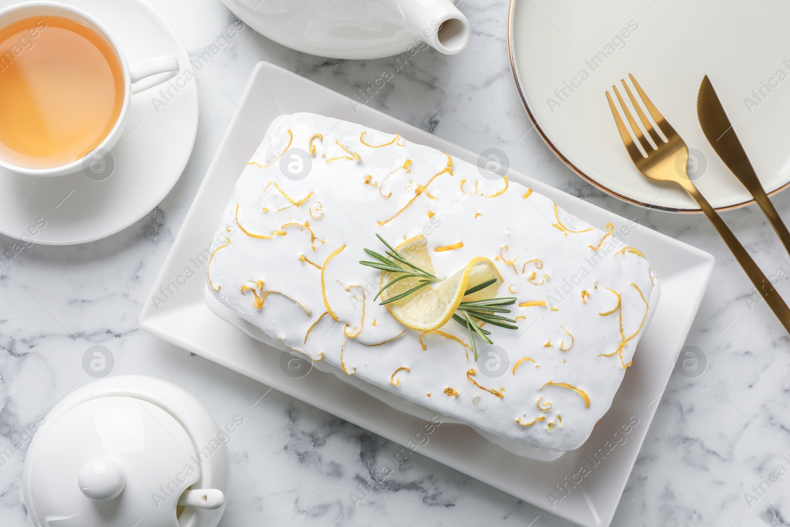 Photo of Tasty lemon cake with glaze served on white marble table, flat lay