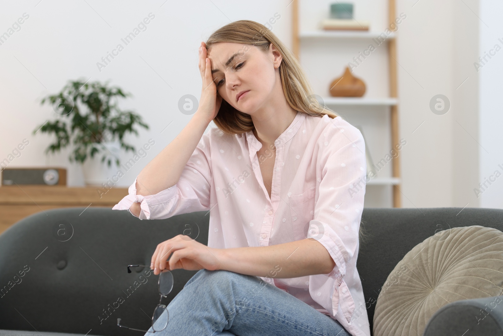 Photo of Overwhelmed young woman suffering from headache at home