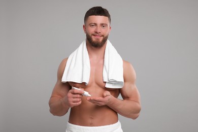 Photo of Handsome man applying body cream on light grey background