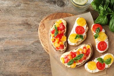 Photo of Tasty fresh tomato bruschettas on wooden table, flat lay. Space for text