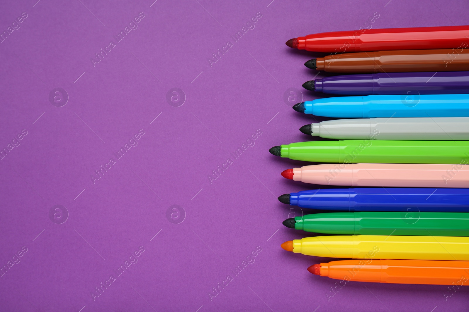 Photo of Different colorful markers on purple background, flat lay. Space for text