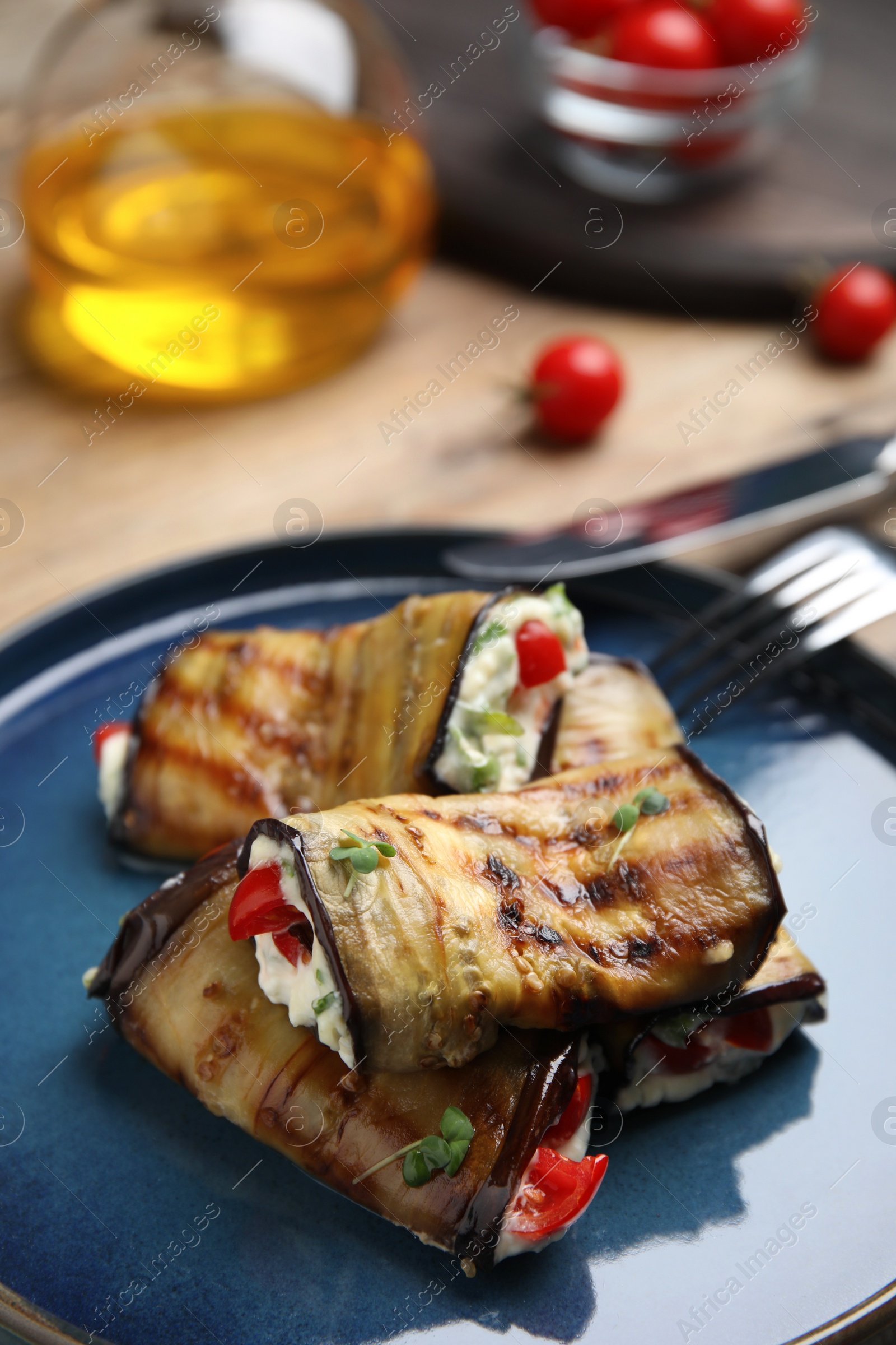 Photo of Delicious baked eggplant rolls with cheese, tomatoes and microgreens on plate, closeup