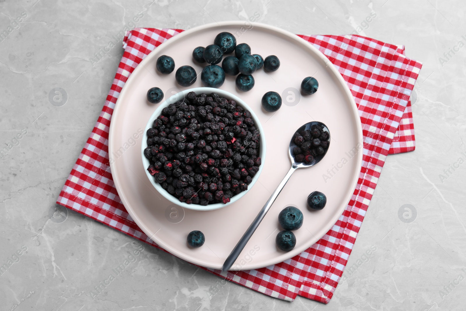 Photo of Freeze dried and fresh blueberries on light grey table, top view