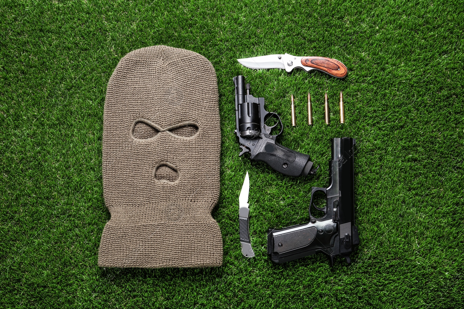 Photo of Flat lay composition with balaclava and weapons on green grass
