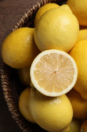 Photo of Fresh lemons in wicker basket on wooden table, closeup
