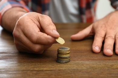 Senior man stacking up coins at table, closeup