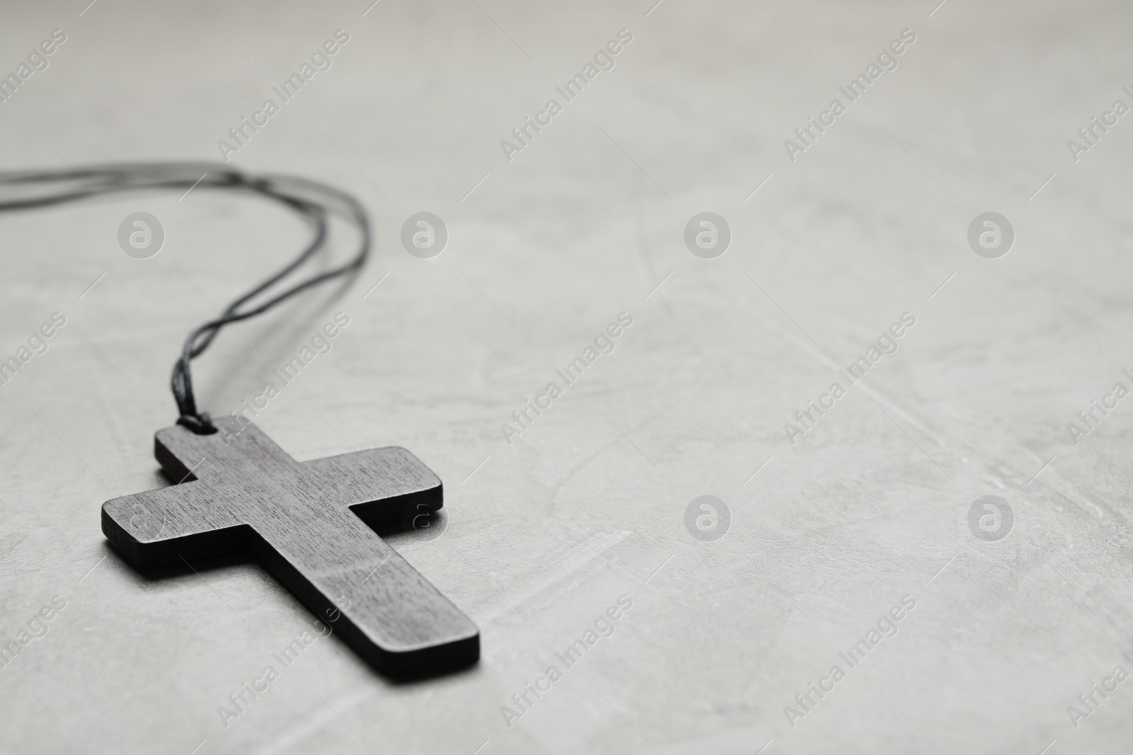 Photo of Wooden Christian cross on light grey table, closeup. Space for text